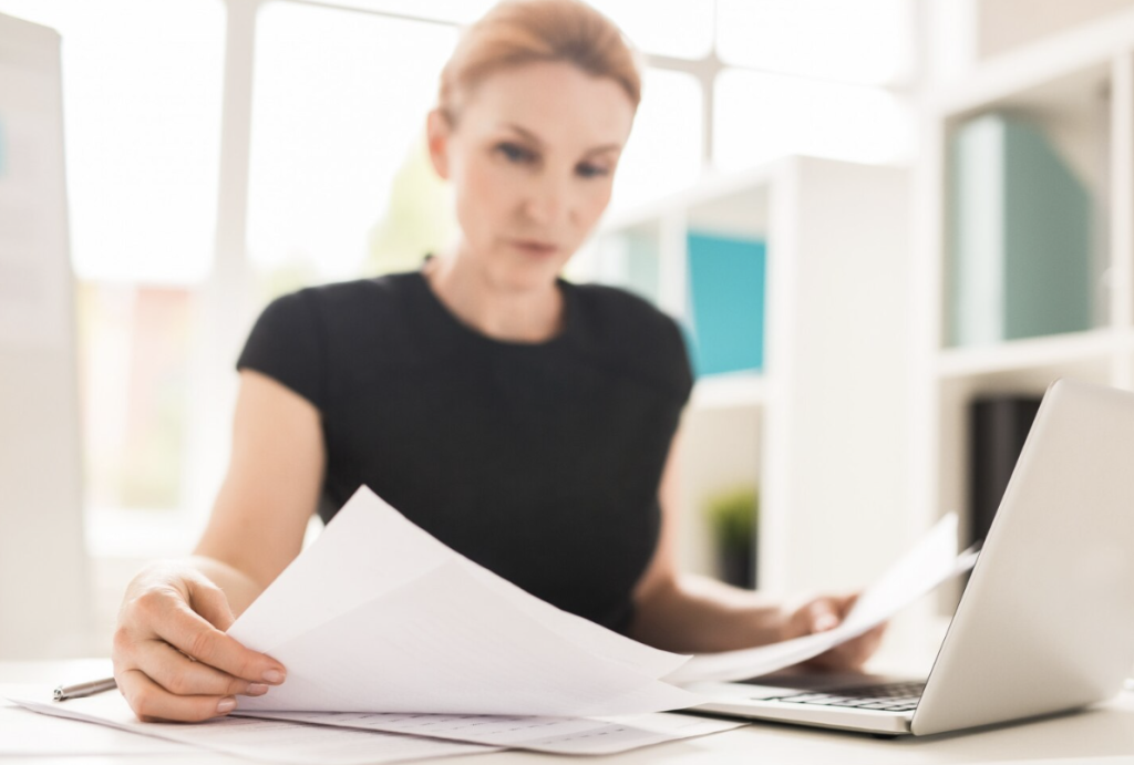 A woman reviewing legal documents at a desk.